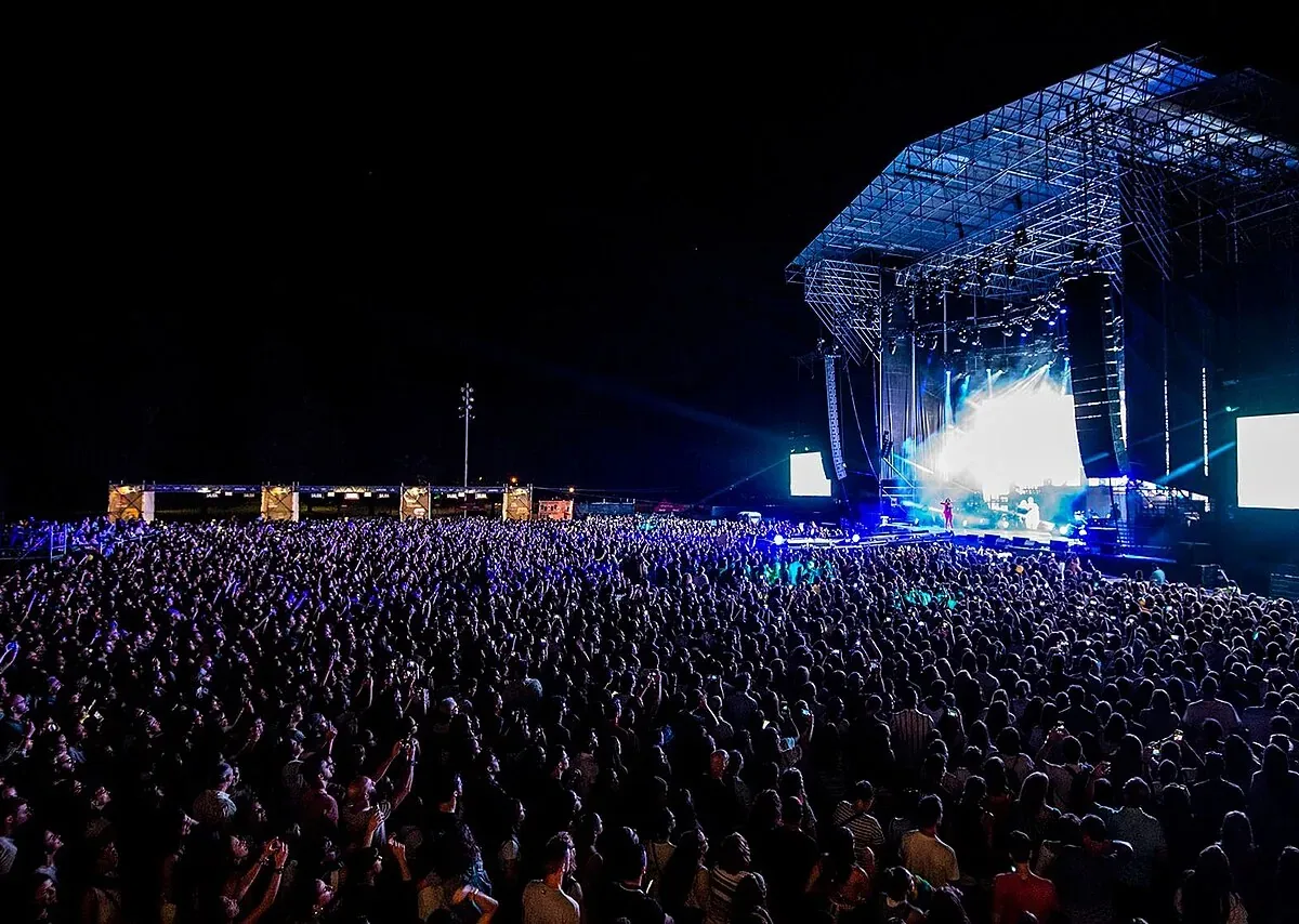 Público ante un gran escenario nocturno en un festival de música al aire libre