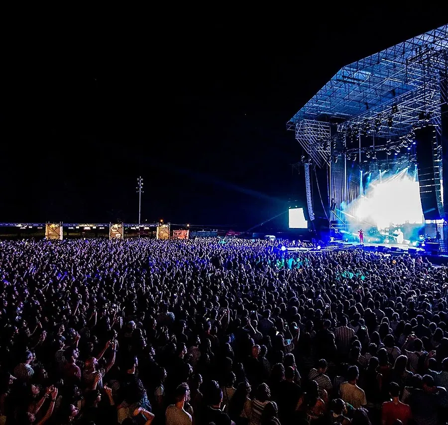 Público ante un gran escenario nocturno en un festival de música al aire libre